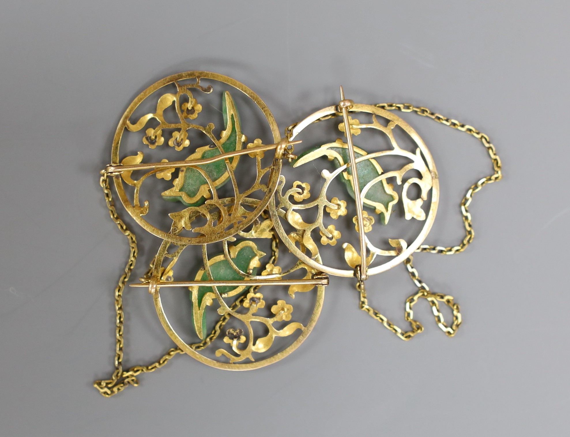 A yellow metal and jade mounted three section circular cloak? brooch, each jade carved as a bird, each section diameter 25mm, with chain attachment and two other yellow metal and jade mounted pins, gross weight 11.7 gram